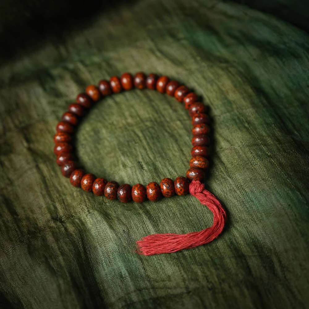 Lotus seed wrist mala on green textile